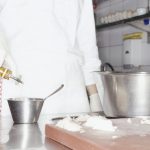 Chef adding olive oil to ingredients in bowl, mid section