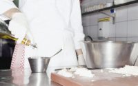 Chef adding olive oil to ingredients in bowl, mid section